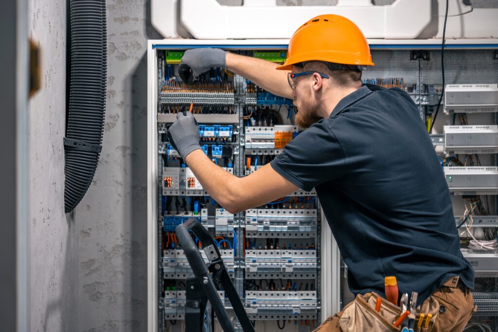 Male electrician working in a switchboard with fuses.